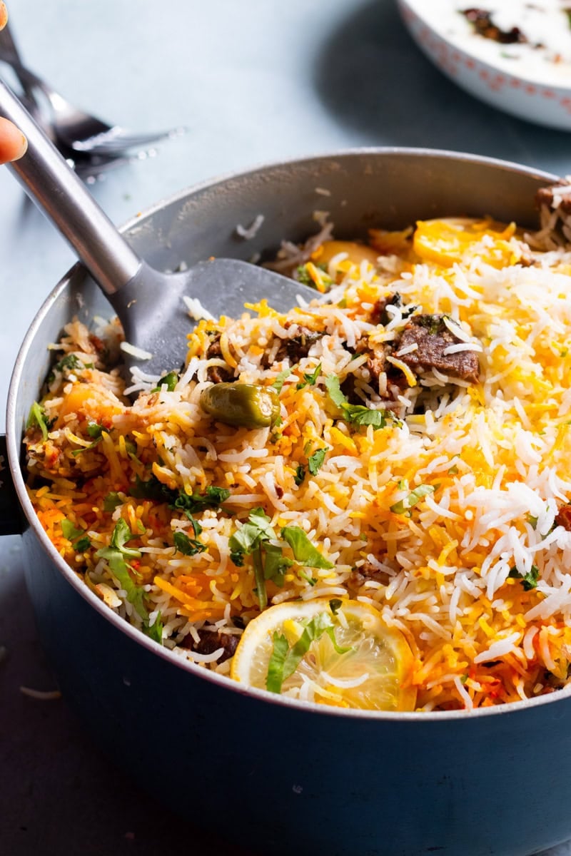 a pot of beef biryani with a spoon in it