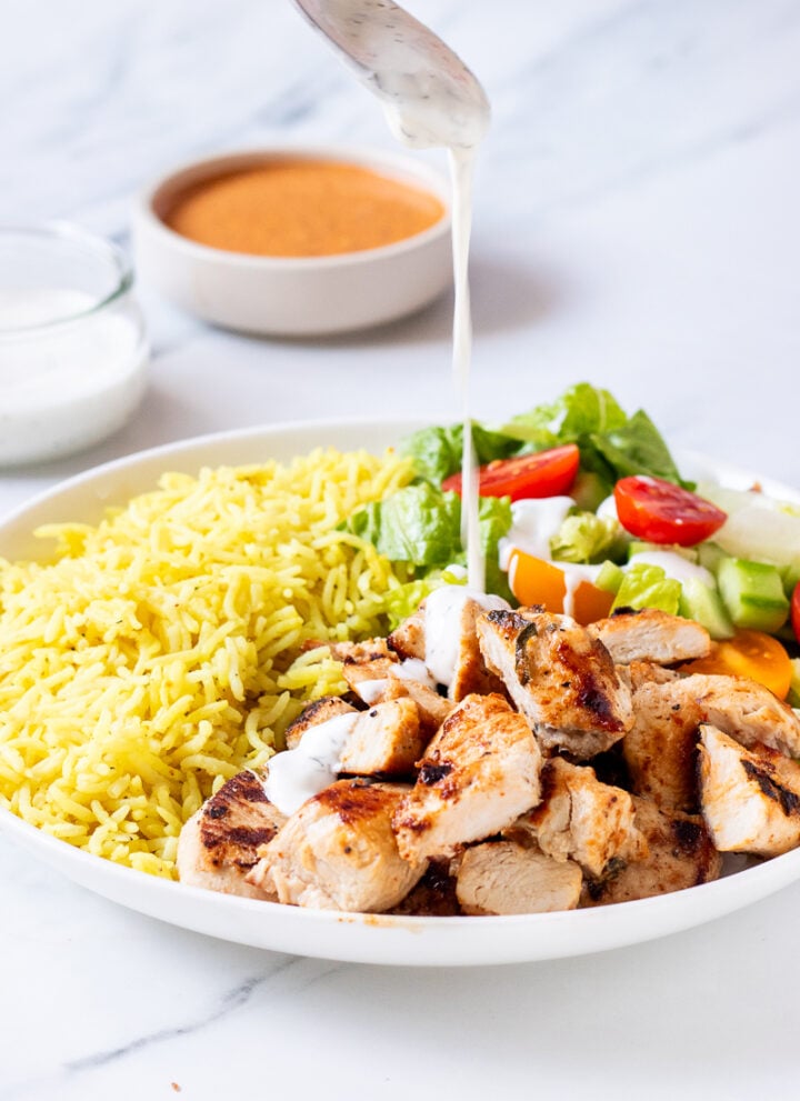 halal cart chicken and rice recipe with white sauce being poured on top