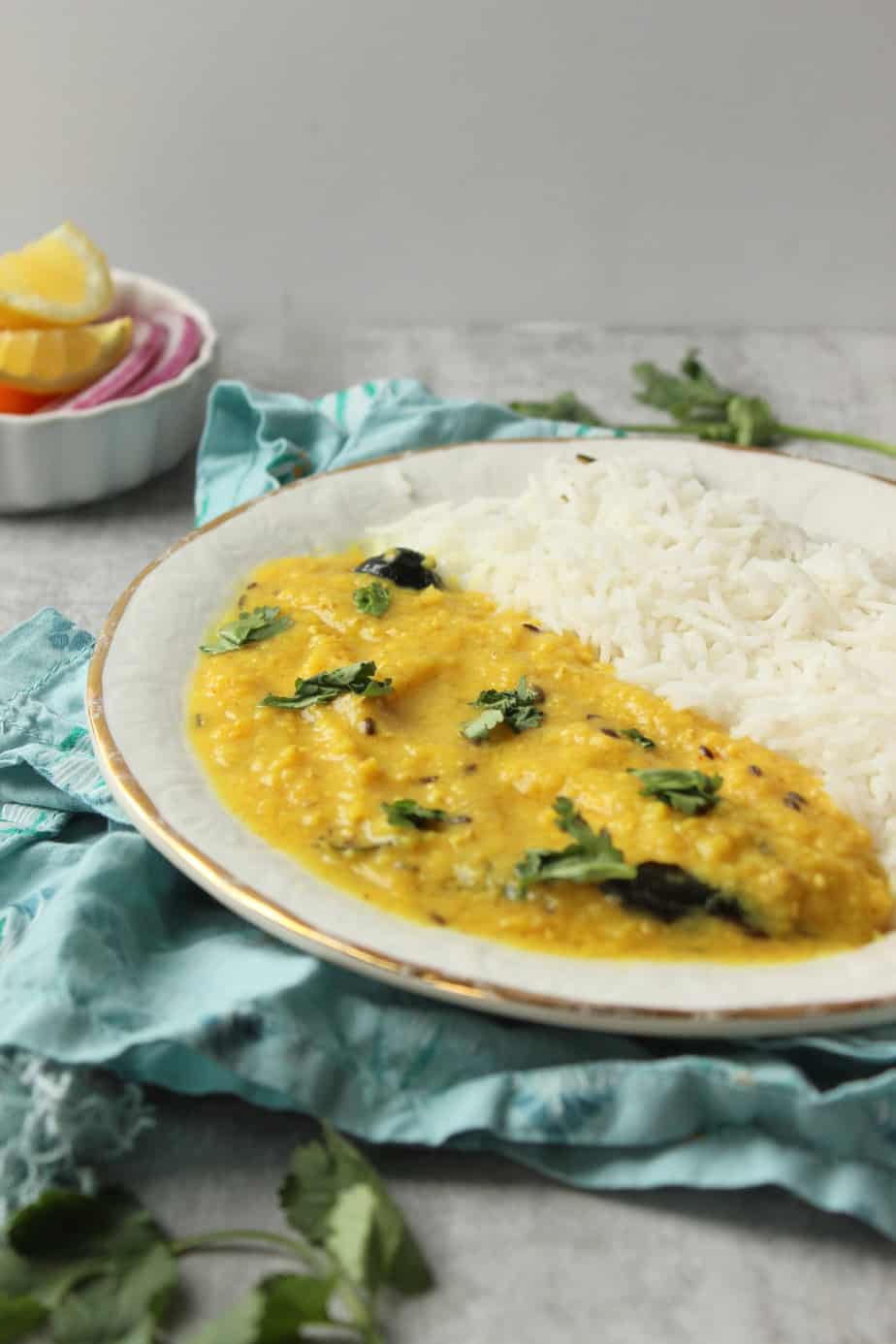 a plate of Khatti Daal with white rice and sliced red onions