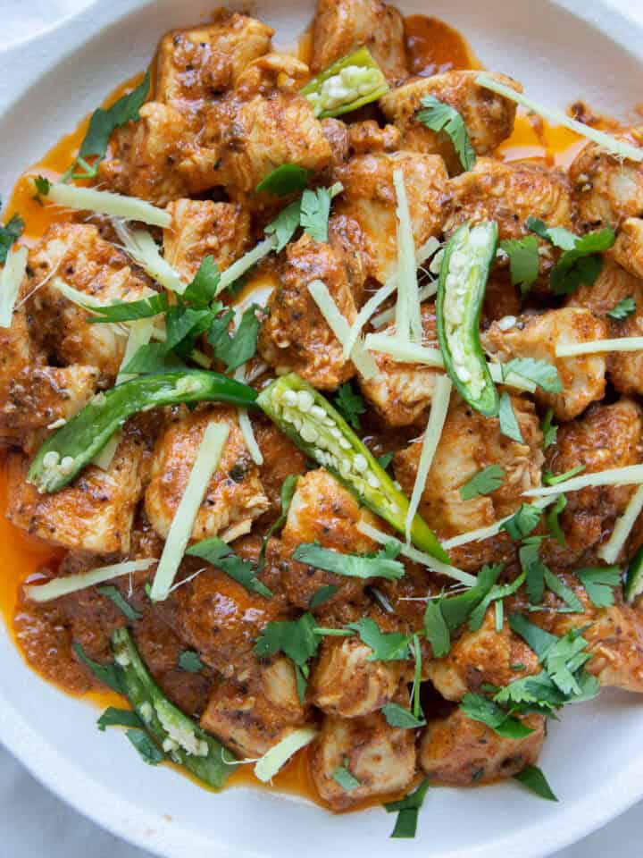 a close up of a dish of Karhai Chicken with green chilies,ciilantro and ginger