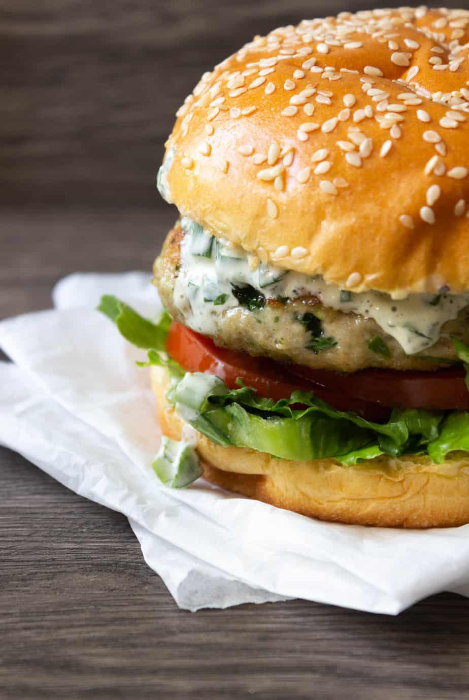 a three quarters shot of a burger assembled, lettuce, tomato and mayo sauce showing