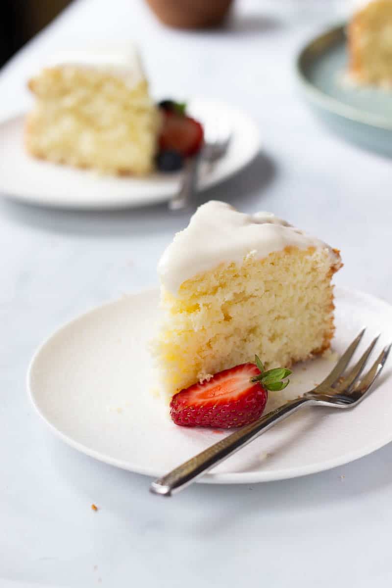 A slice of Easy Lemon Cake with Cream Cheese Glaze and a half strawberry