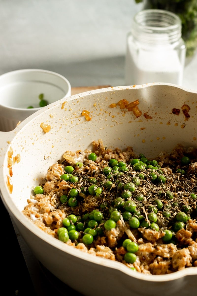 ¾ view of a saute pan with peas and methi on top of the chicken keema 