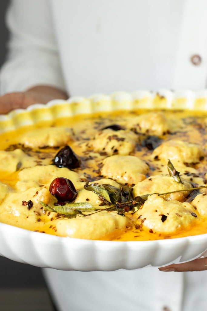 a person holding a dish of Kadhi Pakora or Karhi 