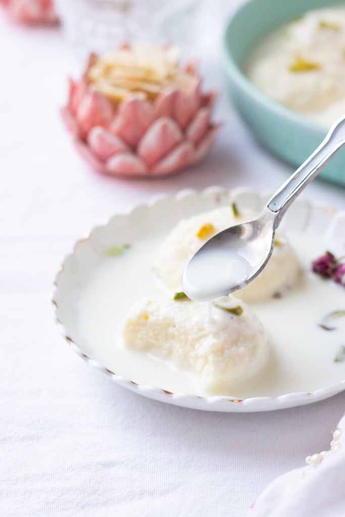 soft rasmalai with some milk being spooned over it 