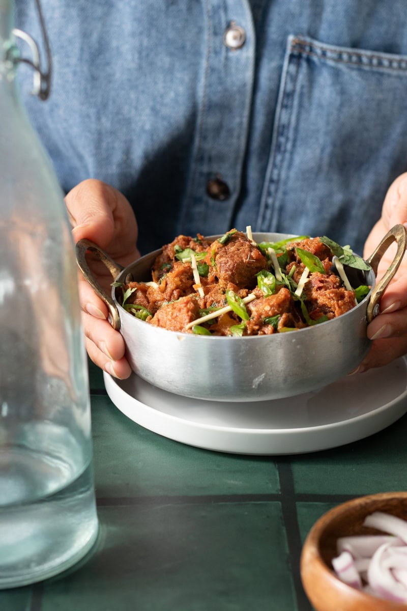 karahi gosht in a pot being held 