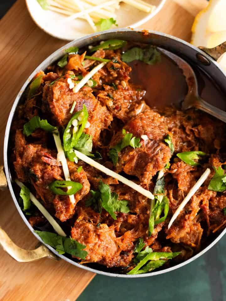 Karahi Gosht top down view with a bowl of ginger in the corner