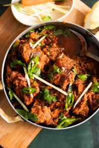 Karahi Gosht top down view with a bowl of ginger in the corner